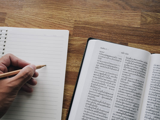 a person is writing on a book with a pencil