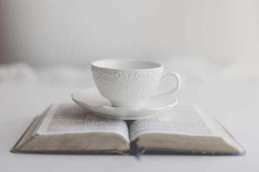 Bíblia aberta com uma chávena de café pousada ao lado, num momento devocional matinal